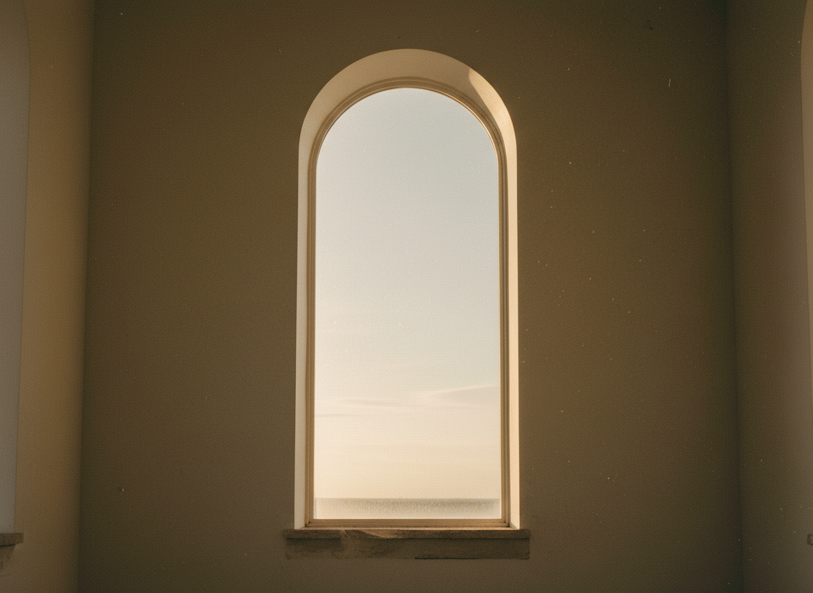 Minimalist still of a classical arched window casting warm light across an ivory stone wall